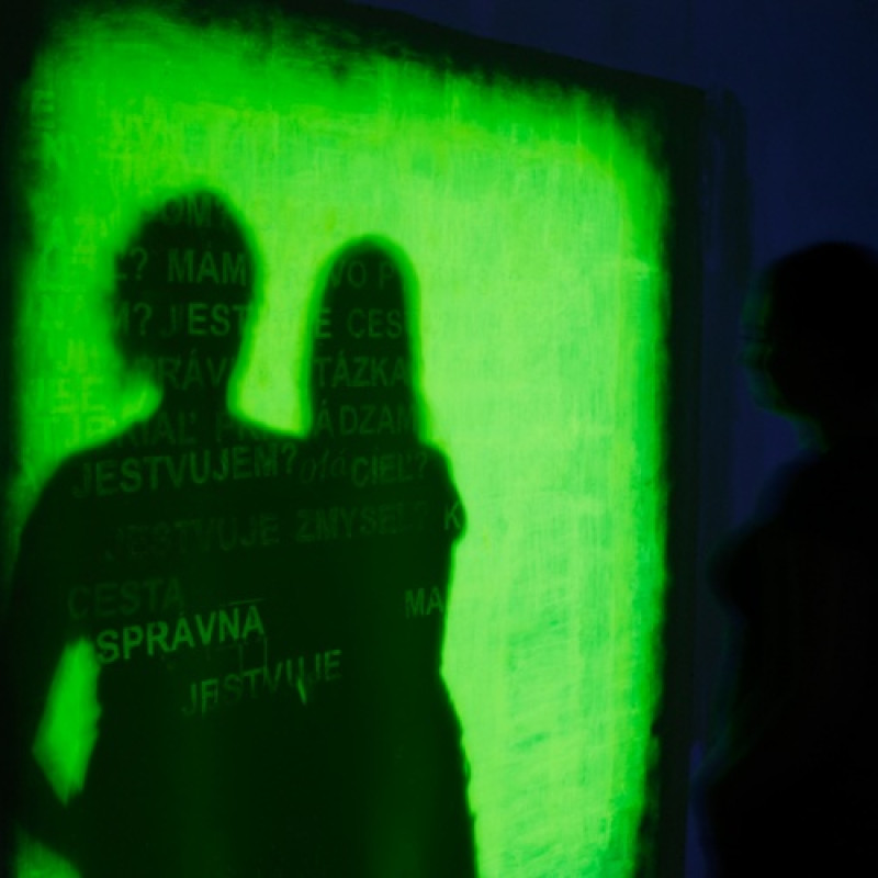 písané a kódované slová, ktoré divák odkrýva svojím tieňom